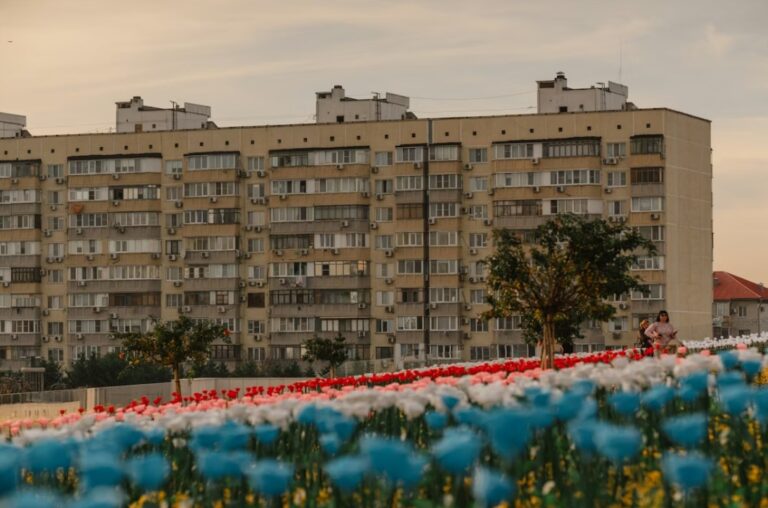 Stambena zgrada u Beogradu sa urbanim parkom i cvećem, simbol tržišta nekretnina i kretanja cena stanova u Srbiji 2026